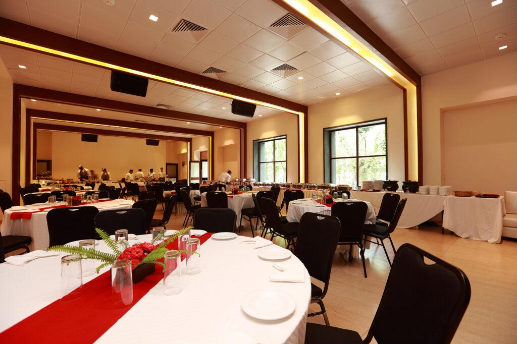 Large banquet hall with round tables with table dressing and plating with a buffet table in the background